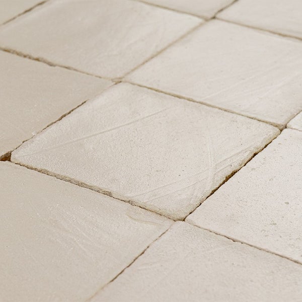 Quadratische Bodenfliesen mit strukturierter Oberflaeche und unregelmaessigen Kanten fuer ein natuerliches Design.