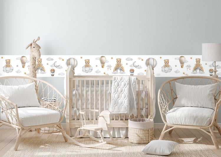 Selbstklebende Tapetenbordüre für das Kinderzimmer mit Motiven von Bären, Regenbögen und Heißluftballons in einem hellen Babyzimmer.