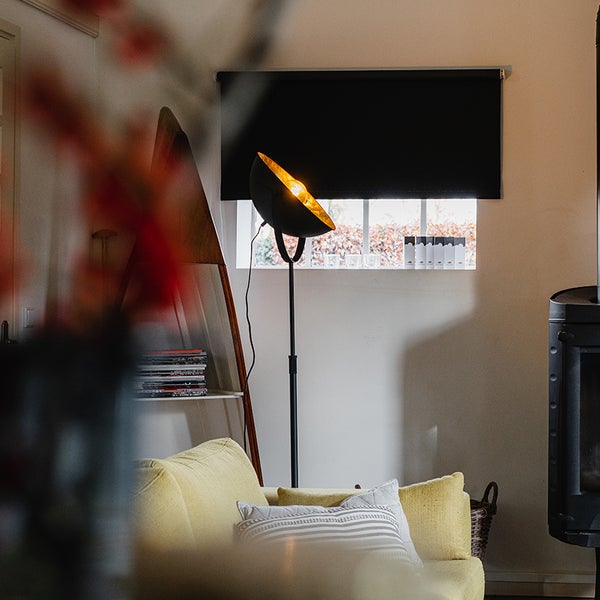 Wohnzimmer mit Stehlampe, Sofa, Regal und Rollladen