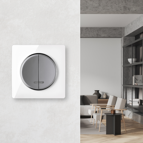 Ein moderner Lichtschalter mit rechteckigem Rahmen und runder Wippe an einer Wand, daneben ein Blick in ein stilvoll eingerichtetes Wohnzimmer.