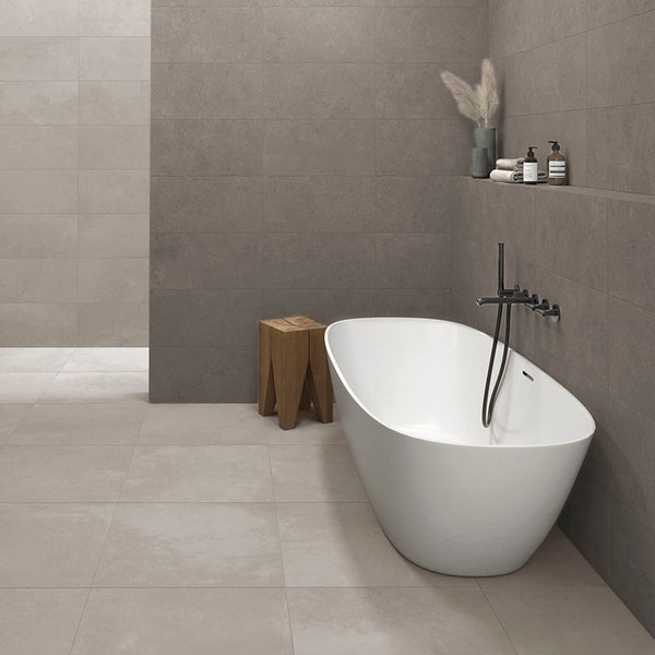 Modernes Badezimmer mit freistehender Badewanne und Wandfliesen in Steinoptik, ergänzt durch einen Holzhocker und eine wandmontierte Armatur.