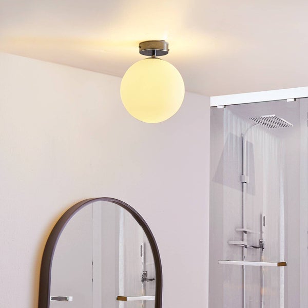 Moderne Deckenleuchte in Kugelform aus Glas, montiert in einem hellen Badezimmer mit Dusche und rundem Spiegel.
