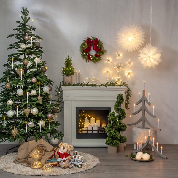 Elektrischer Schwibbogen mit fünf Kerzen neben einem Weihnachtsbaum