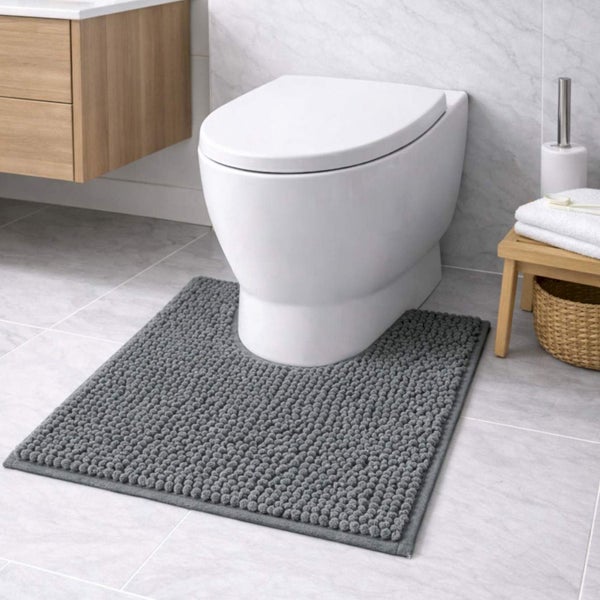 Graue, strukturierte WC-Vorlage mit Ausschnitt vor weißem Wand-WC in modernem Badezimmer mit hellen Fliesen und Holzmöbeln.