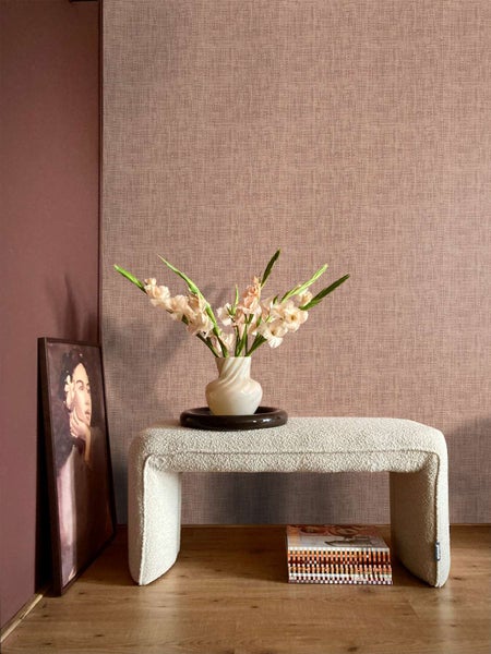 Vliestapete mit feiner Textilstruktur vor einer Wand in einem modern eingerichteten Raum mit Sitzbank und Blumenvase.