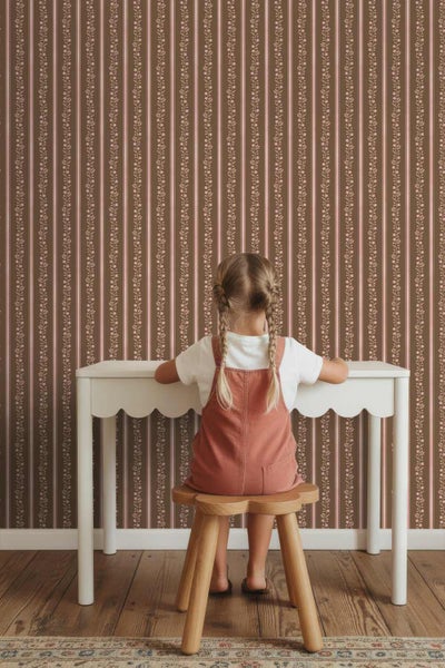 Vliestapete mit vertikalem Streifenmuster und floralen Ranken in einem Kinderzimmer mit Schreibtisch und Holzstuhl.
