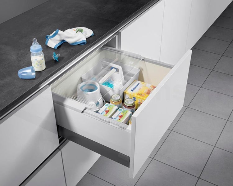 Organisierte Küchenschublade zur Aufbewahrung von Babynahrung, Fläschchen und Zubehör in einer weißen Einbauküche.