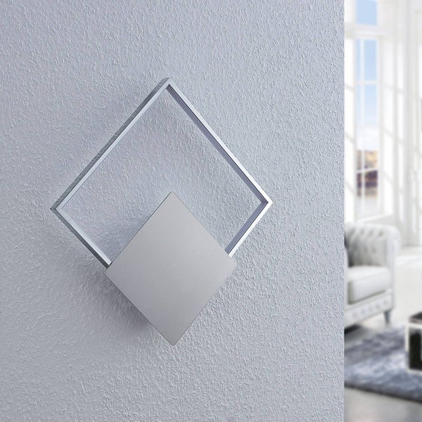 Moderne LED-Wandleuchte in geometrischem Design aus gebürstetem Metall mit zwei überlappenden Rautenformen an einer hellen strukturierten Wand.