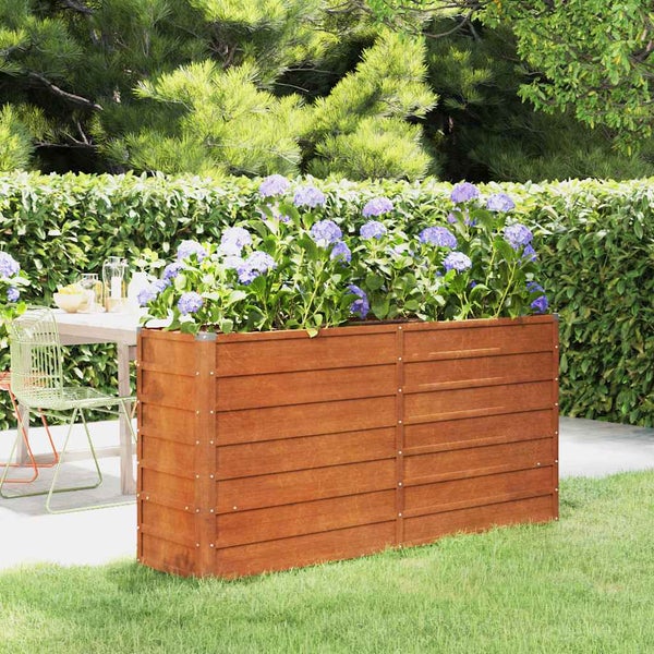 Hochbeet aus Metall in Rost-Optik, bepflanzt mit Hortensien in einem Garten mit Hecke und Terrasse.