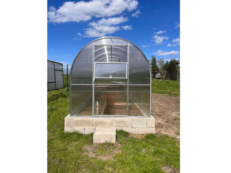 Gewächshaus mit Polycarbonatplatten und Fundament aus Betonsteinen im Garten