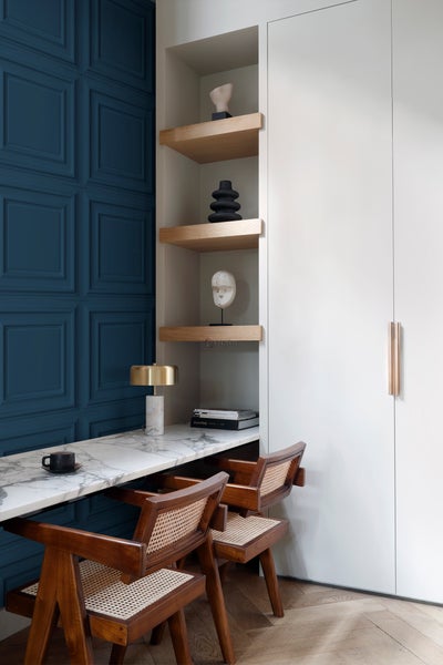Elegantes Arbeitszimmer mit marmorierter Arbeitsplatte, Holzregalen und Stühlen mit Rattansitzen