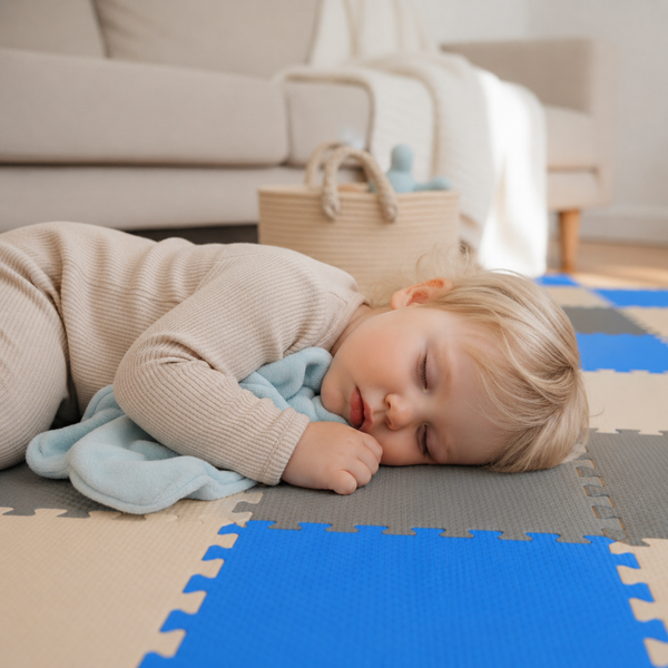 Ein Kleinkind schläft auf einer weichen Schaumstoffpuzzlematte für Kinder im Wohnzimmer.
