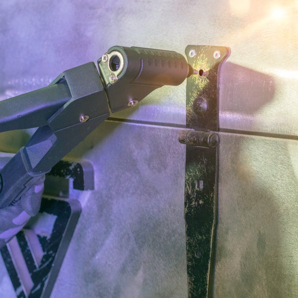 Handnietzange beim Setzen einer Blindniete an einem schwarzen Langband-Scharnier auf einer Metalloberfläche.