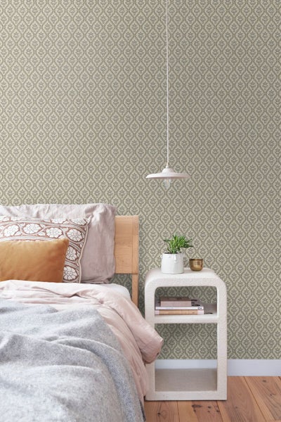 Schlafzimmer mit gemusterter Tapete mit geometrischem Blumenmotiv, Holzbett, weißem Nachttisch und Pendelleuchte.