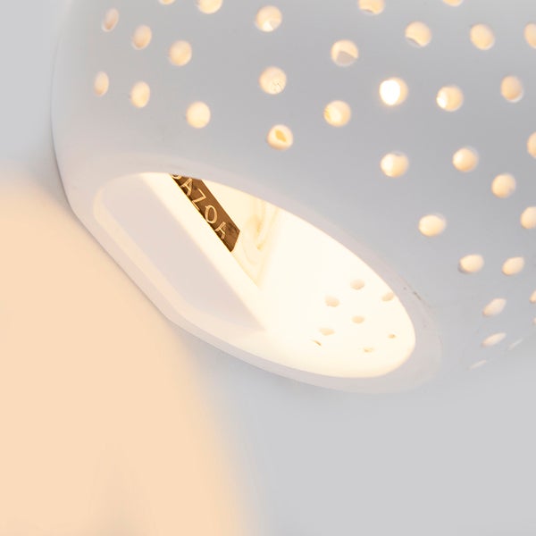 Nahaufnahme einer weißen Wandleuchte mit Lochmuster