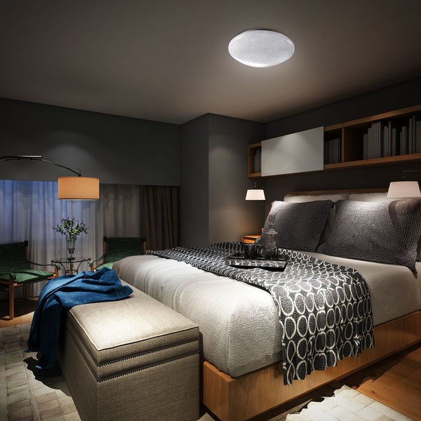 Modernes Schlafzimmer mit runder LED-Deckenleuchte mit Sternenhimmel-Effekt. Der Raum bietet ein großes Bett, Holzregale und gemütliches Licht.