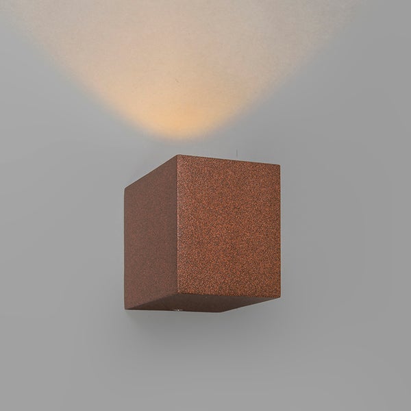 Würfelförmige Wandleuchte in Rostoptik mit Lichtstrahl nach oben.