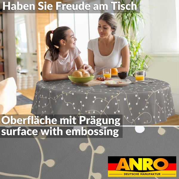 Rundes Tischtuch mit geprägter Oberfläche und Zweigmuster, präsentiert in einer Frühstücksszene mit Mutter und Kind. ANRO Logo.