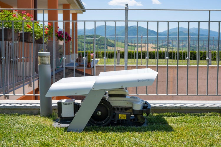 Rasenmähroboter auf Rasenfläche mit Bergpanorama im Hintergrund
