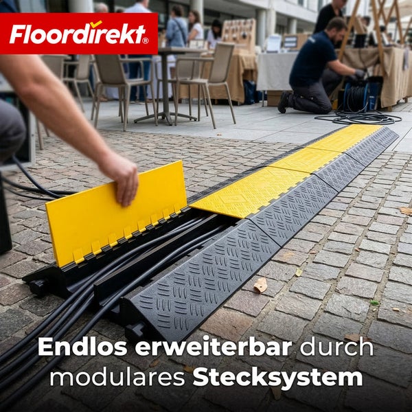 Floordirekt Logo. Modulare Kabelbrücke aus Kunststoff in Schwarz und Gelb auf Kopfsteinpflaster, endlos erweiterbar durch ein Stecksystem.