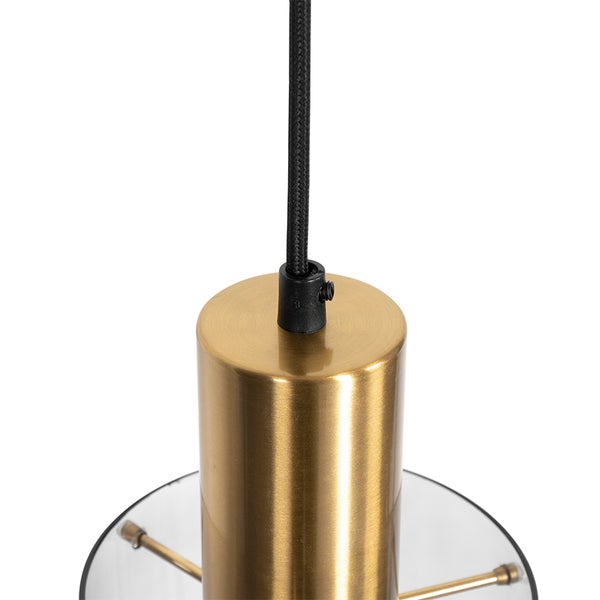 Detailaufnahme einer Pendelleuchte mit goldfarbenem Metallzylinder, schwarzem Textilkabel und Glasschirm.
