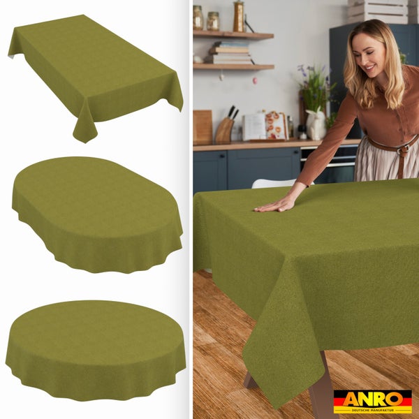 Grüne Stofftischdecke in rechteckiger, ovaler und runder Form. Frau glättet Decke auf Holztisch in heller Küche. ANRO Deutsche Manufaktur Logo.