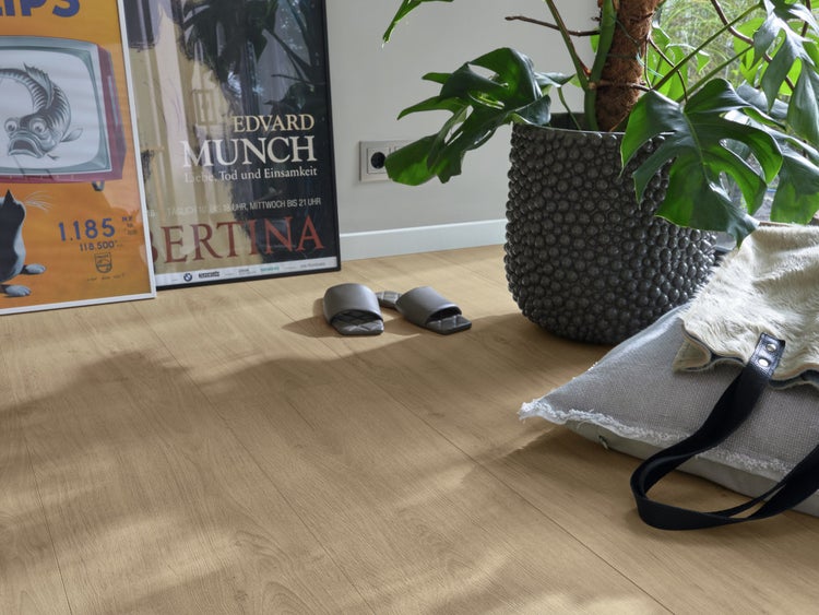 Wohnraum mit Eichenparkett Bodenbelag, dekorativen Postern, einer großen Pflanze im Topf und Wohnaccessoires in einer modernen Umgebung.