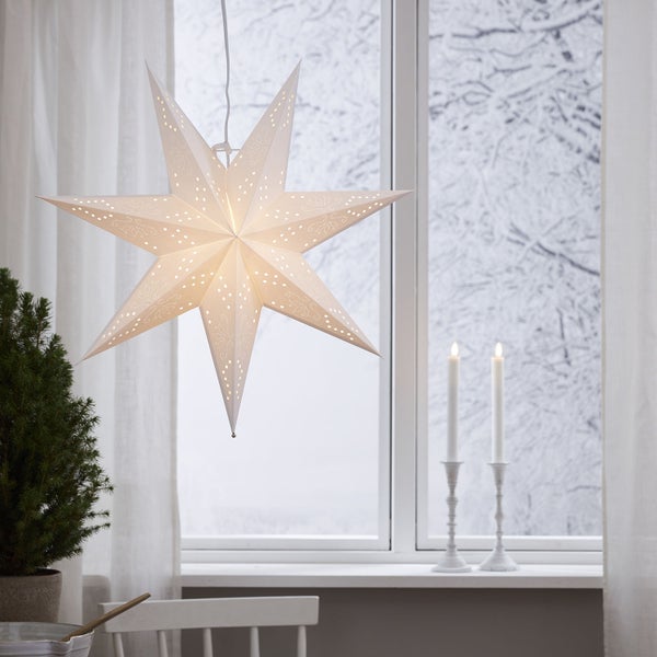 Dekorativer Papierstern hängt im Raum vor einem Fenster.