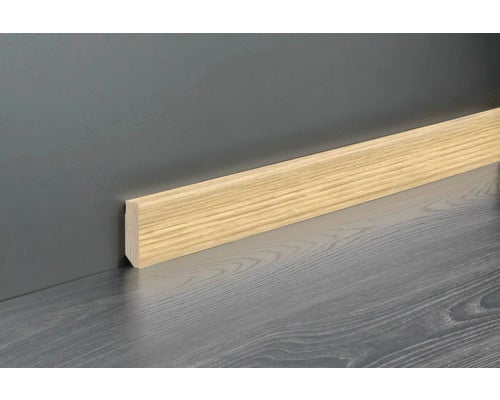 Sockelleiste in Eichenoptik montiert an einer Wand über einem Boden mit Holzstruktur.