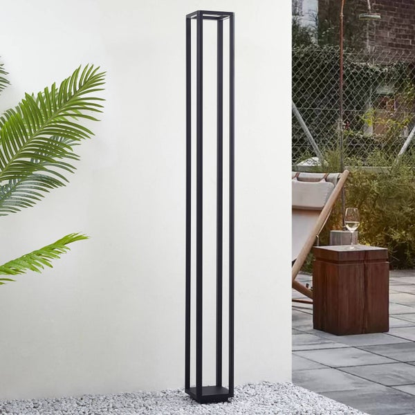 Moderne schwarze Außenstehleuchte in minimalistischem Design auf einer Terrasse mit Kies vor einer Wand.