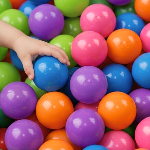 Kinderhand greift nach Kunststoff-Spielbällen für ein Bällebad, versehen mit der europäischen Konformitätskennzeichnung.