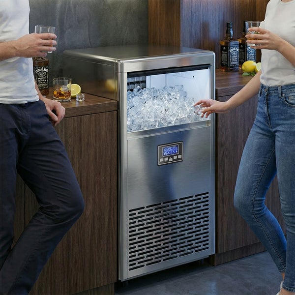 Moderne Eiswürfelmaschine aus Edelstahl mit Digitalanzeige und beleuchtetem Innenraum voller Eiswürfel, integriert in Holzschränke einer Küche.