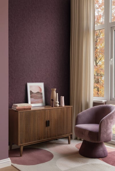 Modernes Wohnzimmer mit dunkelvioletter gemusterter Tapete, Sideboard aus Holz mit vertikalen Lamellen und lila Samtsessel.