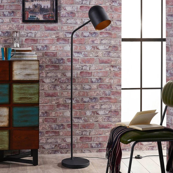 Innenaufnahme eines Zimmers mit einer Stehlampe, einem Schrank und einem Stuhl vor einer Ziegelwand