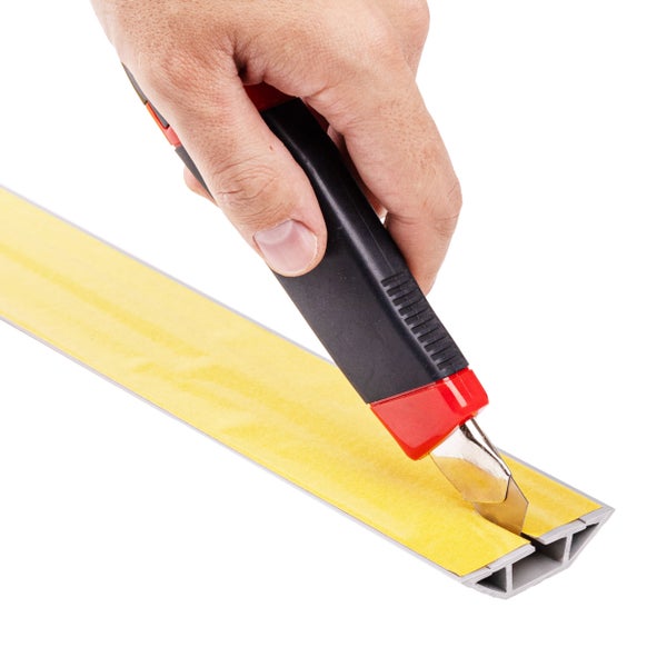 Eine Hand schneidet mit einem Cuttermesser ein selbstklebendes Profil zu.