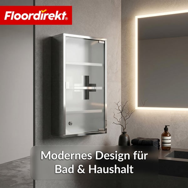 Floordirekt Logo. Moderner Arzneischrank aus Edelstahl mit satinierter Glastür und Erste Hilfe Symbol an einer Wand im Badezimmer neben einem Spiegel.