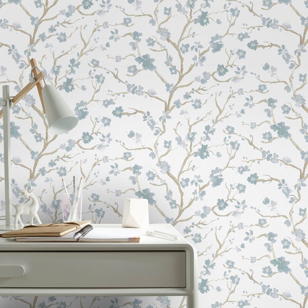 Wand mit Blumentapete und Schreibtisch mit Büromaterialien