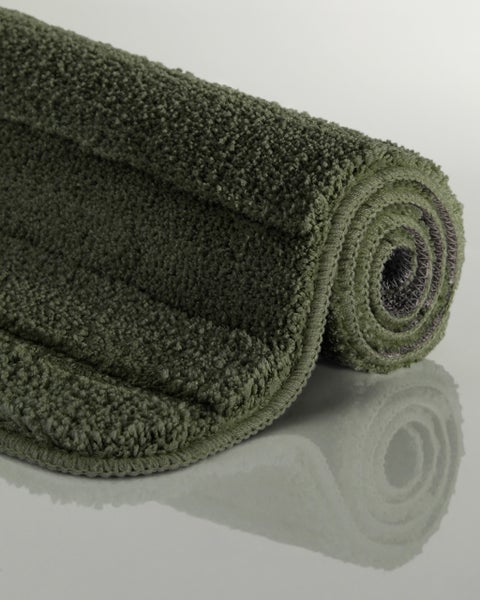 Eingerollte Badematte aus weichem, flauschigem Textil in Dunkelgrün.