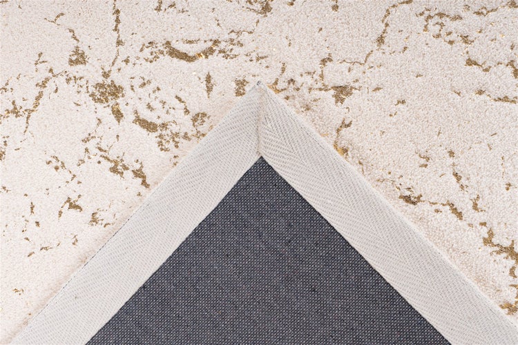 Nahaufnahme eines Teppichs mit Marmormuster und goldfarbenen Akzenten, umgeschlagene Ecke zeigt die Rückseite und die Webkante.
