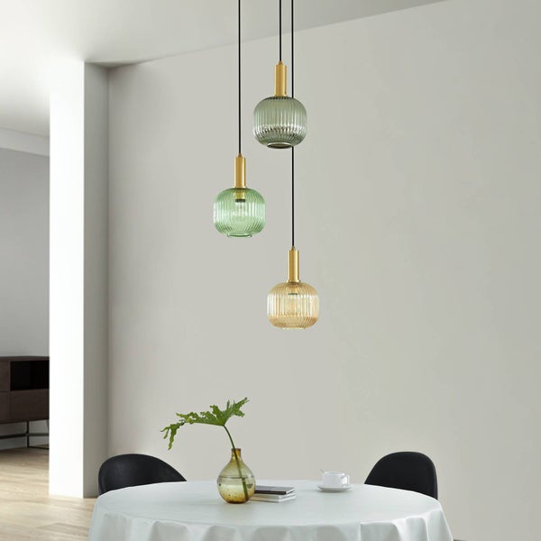 Dreiflammige Pendelleuchte mit geriffelten Glasschirmen in Grün und Bernstein und goldfarbenen Fassungen in einem hellen, modernen Esszimmer.