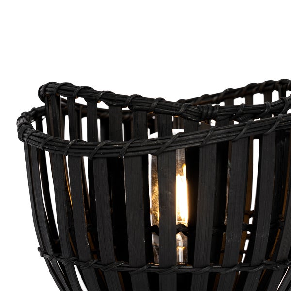 Schwarze Tischleuchte aus Rattan mit eingeschalteter Glühbirne