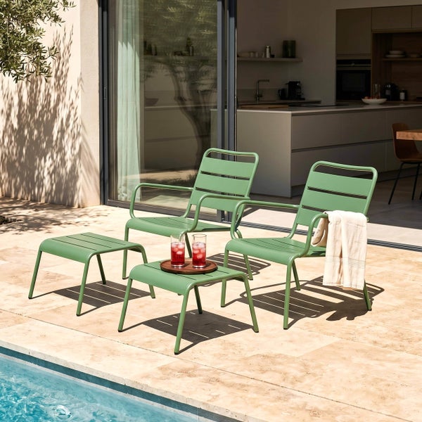Gartenmöbel-Set aus Metall mit zwei Sesseln, einem Beistelltisch und einem Fußhocker auf einer hellen Steinterrasse am Pool.