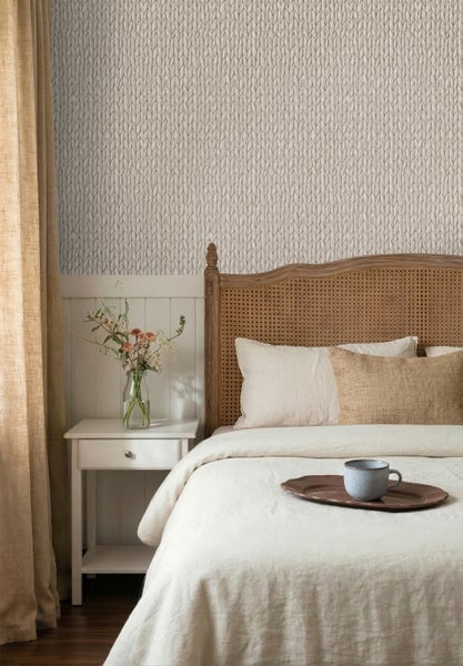 Schlafzimmer mit Wandtapete in Strickoptik, Bett mit Kopfteil aus Wiener Geflecht und weißem Nachtschrank.