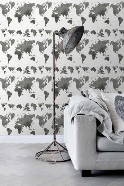 Dekorative Wand mit Weltkartenmuster, ergänzt durch Stehlampe und Couchgarnitur für ein stilvolles Interieur.