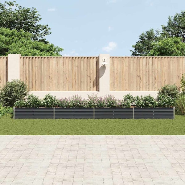 Gartenansicht mit erhöhtem Beet aus Metall, das mit Pflanzen bepflanzt ist, vor einem Holzzaun.