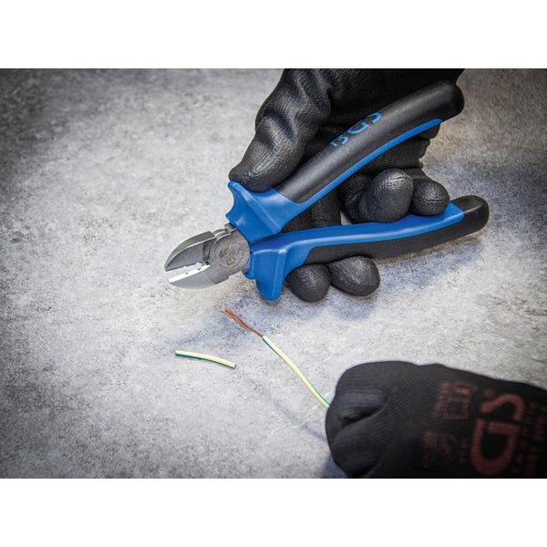 Nahaufnahme einer Hand mit Arbeitshandschuh, die mit einer Seitenschneider Zange ein Kabel schneidet.