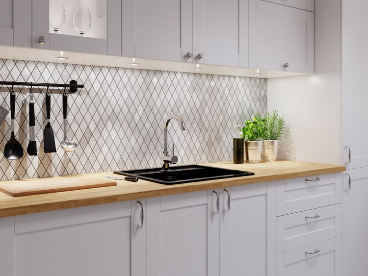 Moderne Küche mit grauen Schränken im Landhausstil, Holzarbeitsplatte, schwarzem Spülbecken, Chrom-Armatur und Fliesenspiegel im Rautenmuster.