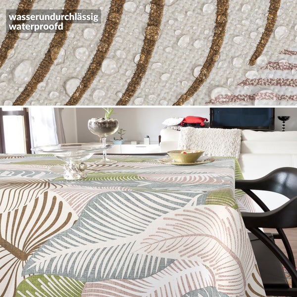 Wasserundurchlässige Tischdecke mit Blattmuster in einem hellen Wohnzimmer. Nahaufnahme zeigt Wassertropfen auf der Stoffoberfläche.