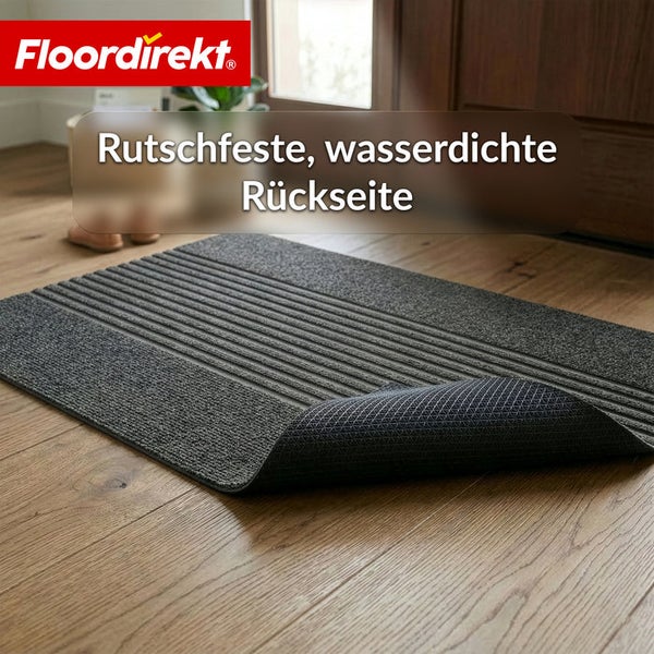 Floordirekt Logo. Dunkelgraue Fußmatte auf Holzboden mit rutschfester und wasserdichter Rückseite.