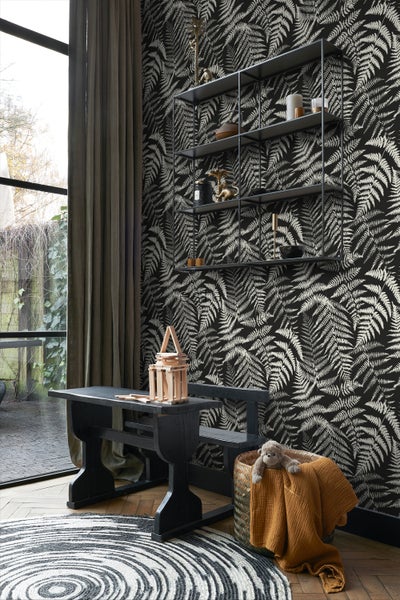 Wohnraum mit Farnmuster-Tapete, schwarzem Tisch, Regal und rundem Teppich